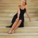 Dame trägt schwarzes Boho Kleid als Hochzeitsgast und sitzt auf einer treppe