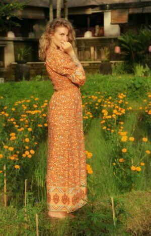 produkt bild Boho Maxikleid mit Sweetheart Ausschnitt und hohem seitlichen Schlitz Blumenprint Terrakotta getragen von Dame stehend im Grünen Feld.